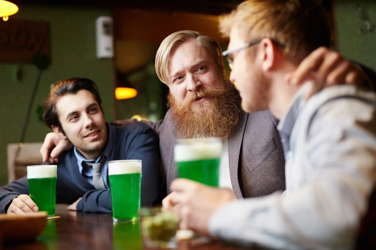 3 homens a conversar amigávelmente, enquanto bebem