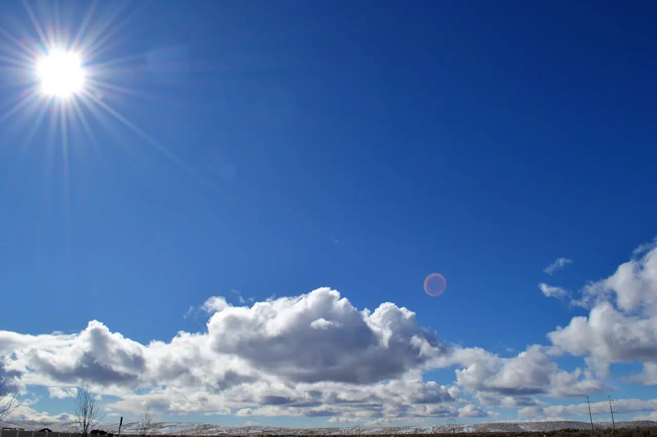 céu azul com um sol brilhante e algumas nuvens