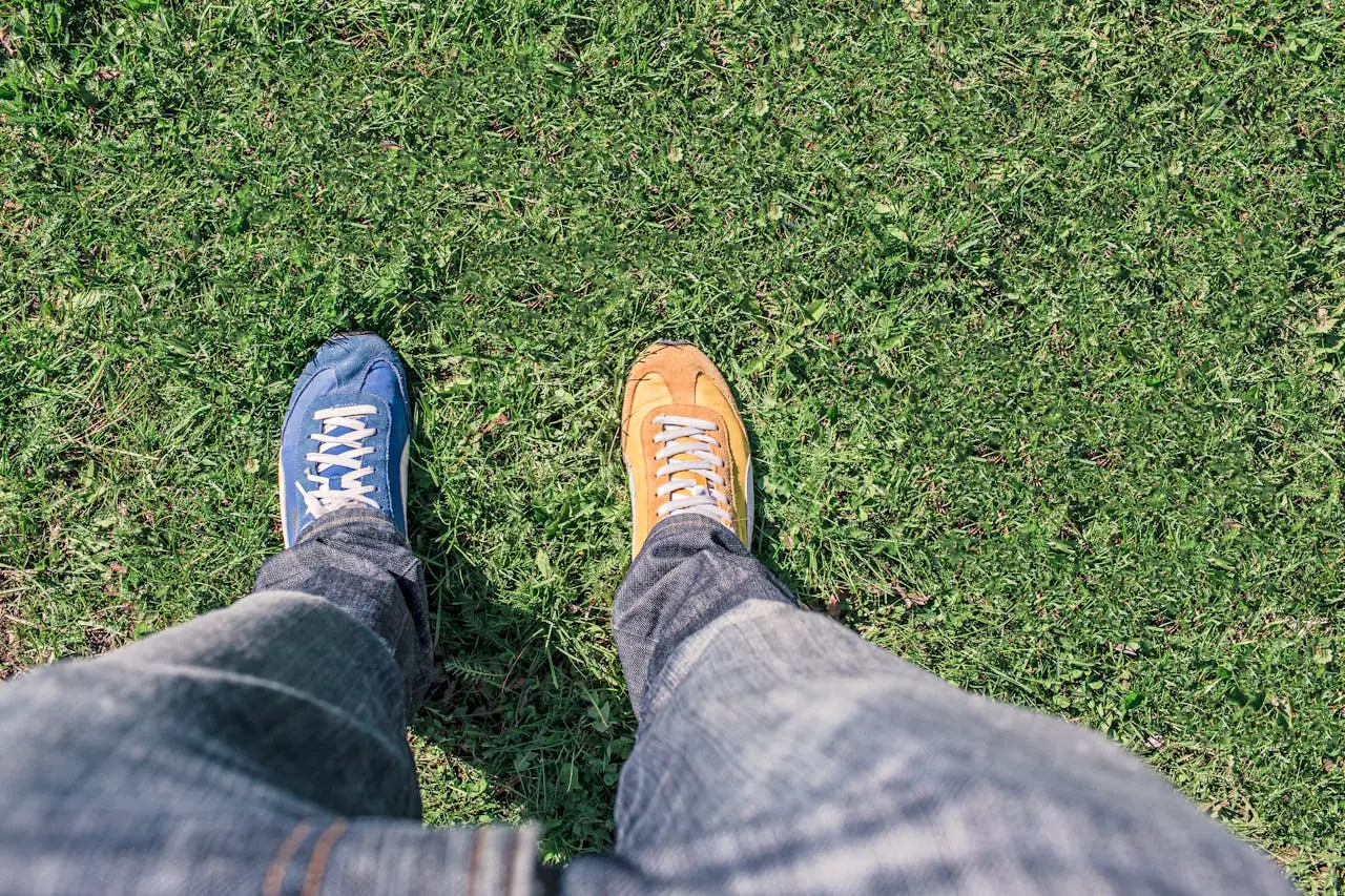 top-down view of man standing on grass with two different shoe colors